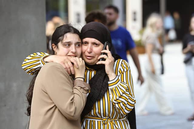 People evacuated from the Fields shopping center react, in Orestad, Copenhagen, Denmark, Sunday, July 3, 2022, after reports of shots fired. Danish police say several people have been shot at a Copenhagen shopping mall. Copenhagen police said that one person has been arrested in connection with the shooting at the FieldÕs shopping mall on Sunday. Police tweeted that Òseveral people have been hitÓ but gave no other details. (Olafur Steinar Gestsson /Ritzau Scanpix via AP)