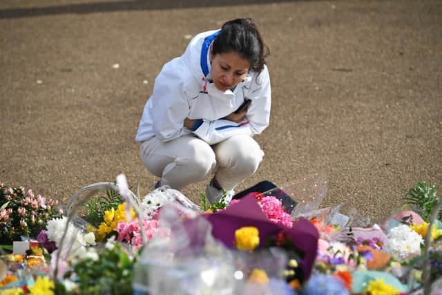 A woman looks at floral tributes left at the band stand in Clapham Common, London, for Sarah Everard.