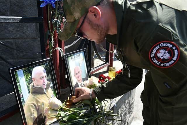 A member of private mercenary group Wagner pays tribute to Yevgeny Prigozhin and Dmitry Utkin, a shadowy figure who managed Wagner's operations and allegedly served in Russian military intelligence, at the makeshift memorial in front of the PMC Wagner office in Novosibirsk.