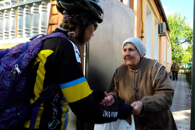 Viktoria, a cycle volunteer, delivers food to Larysa, an older resident of Kharkiv. DEC charity CAFOD is working in partnership with Depaul Ukraine to ensure food baskets reach 700 people on a regular basis.