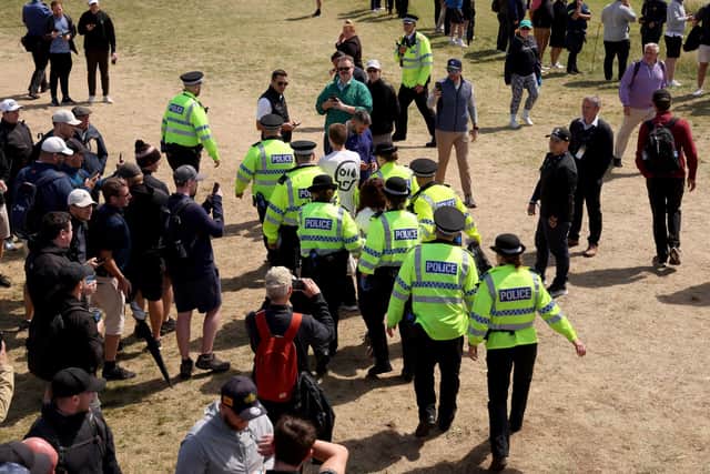 Police Officers remove Just Stop Oil protesters from the course, after interrupting play and throwing orange paint and glitter onto the edges of the green on the 17th hole.