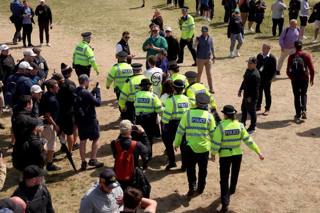 Police Officers remove Just Stop Oil protesters from the course, after interrupting play and throwing orange paint and glitter onto the edges of the green on the 17th hole.