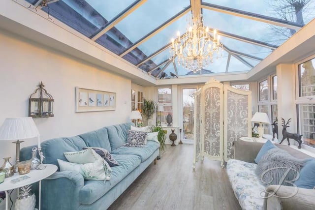 A second image of the conservatory, which offers gorgeous views of the garden, front and back. It has laminate flooring and double doors leading outside.
