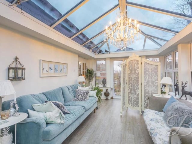 A second image of the conservatory, which offers gorgeous views of the garden, front and back. It has laminate flooring and double doors leading outside.