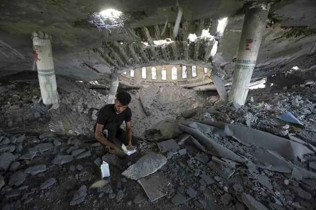 A man looks at damaged books inside a mosque destroyed in an Israeli air strike in Khan Younis, Gaza Strip. The Hamas militants broke out of the blockaded Gaza Strip and rampaged through nearby Israeli communities, taking captives, while Israel's retaliation strikes leveled buildings in Gaza. (AP Photo/Yousef Masoud)