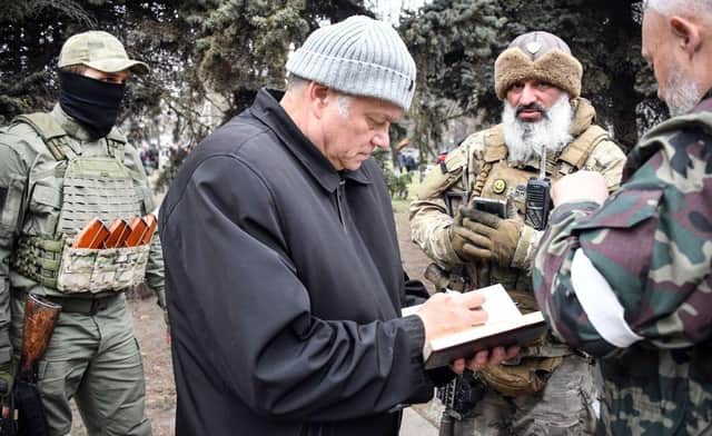 Konstantin Ivashchenko, former CEO of the Azovmash plant and newly appointed pro-Russian mayor of Mariupol writes notes flanked by his bodyguards, in Mariupol.