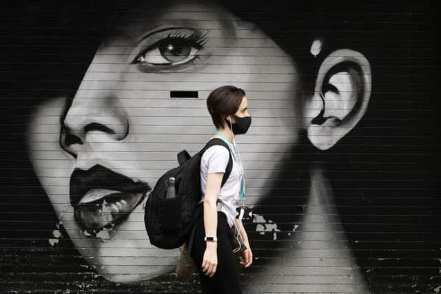 A woman wearing a protective face mask walks through Glasgow city centre.