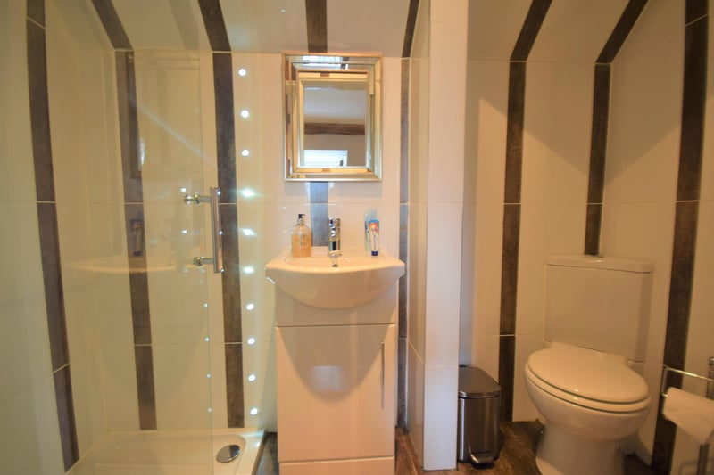 The handy ensuite boasts a shower cubicle with wall mounted inset lights, WC, wash hand basin with storage cupboard unit, chrome mixer tap and tiles to the walls.