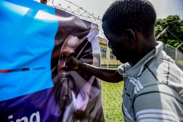 A man punches a banner with a picture of former child soldier-turned-warlord Dominic Ongwen before a screening in Lukodi, Uganda, of the start of his International Criminal Court trial in 2016 (Picture: Isaac Kasamani/AFP via Getty Images)