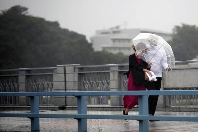People share an umbrella against strong wind and rain as they walk on a bridge in Kawasaki, near Tokyo. Picture: AP Photo/Eugene Hoshiko