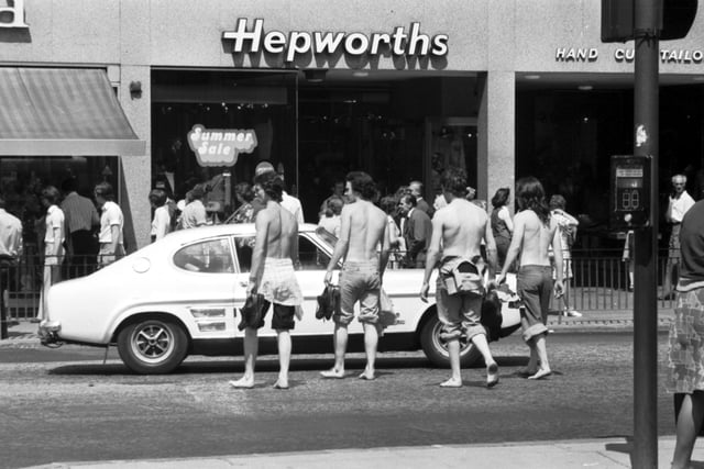 Four teenagers stripped to the waist and in bare feet crossing Princes Street Edinburgh during the long hot summer of 1976.