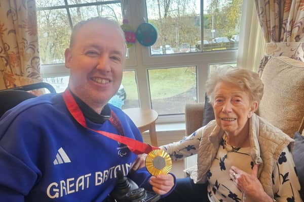 Paralympian Stephen McGuire shows his gold medal to resident May Wilson
