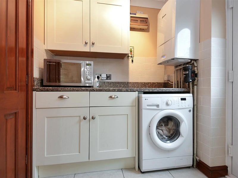 There are contemporary wall and base units, granite-effect work surfaces and plumbing for a washing machine.