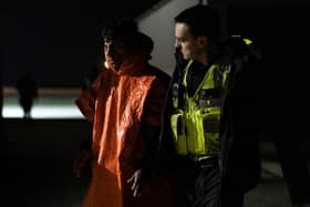 A man is escorted by Border Force officials after being picked up in the channel with other migrants on the south coast of England.