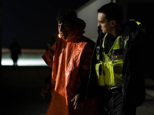 A man is escorted by Border Force officials after being picked up in the channel with other migrants on the south coast of England.