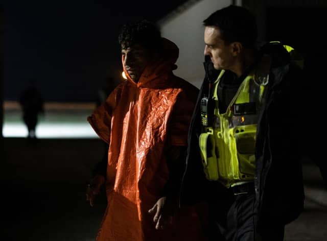 A man is escorted by Border Force officials after being picked up in the channel with other migrants on the south coast of England.