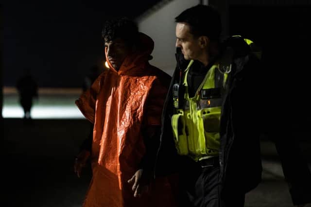 A man is escorted by Border Force officials after being picked up in the channel with other migrants on the south coast of England.