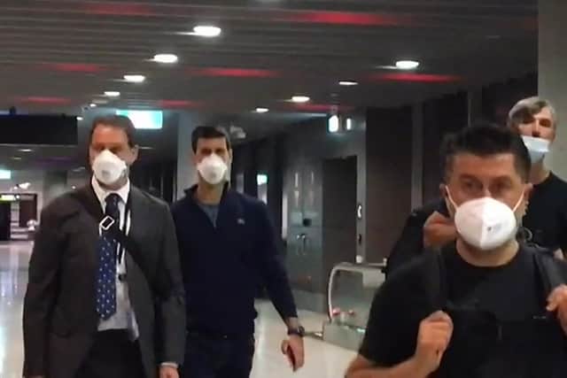 A screen grab from AFPTV shows Serbia's Novak Djokovic (2nd L) preparing to depart from Melbourne Airport after losing a sensational legal battle over his coronavirus vaccination status with his dream of clinching a record 21st Grand Slam in tatters. (Photo by MELL CHUN/AFP via Getty Images)