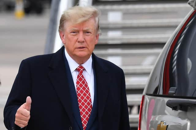 Former US President Donald Trump gestures to members of the media on the tarmac after disembarking "Trump Force One" at Aberdeen airport