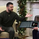 President of Ukraine Volodymyr Zelensky presents a medal from a Ukrainian soldier to U.S. President Joe Biden during a meeting in the Oval Office of the White House