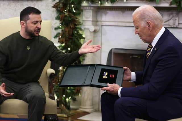 President of Ukraine Volodymyr Zelensky presents a medal from a Ukrainian soldier to U.S. President Joe Biden during a meeting in the Oval Office of the White House