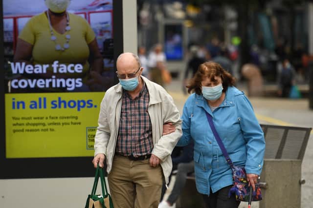 Shoppers wear face masks as they walk by an NHS poster urging people to wear them in shops (Picture: Oli Scarff/AFP via Getty Images)