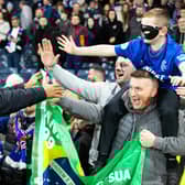 Rangers striker Danilo hands over his mask to a fan at full time.