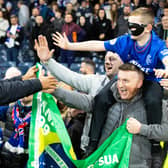 Rangers striker Danilo hands over his mask to a fan at full time.
