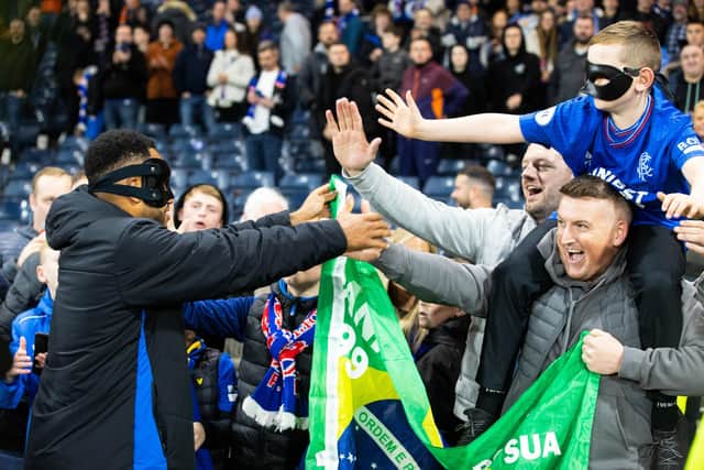 Rangers striker Danilo hands over his mask to a fan at full time.
