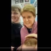 The video shows Nicola Sturgeon not wearing a face mask in a public setting.