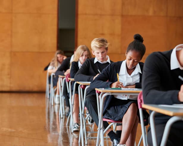 Teenage Students In Uniform Sitting Examination In School Hall