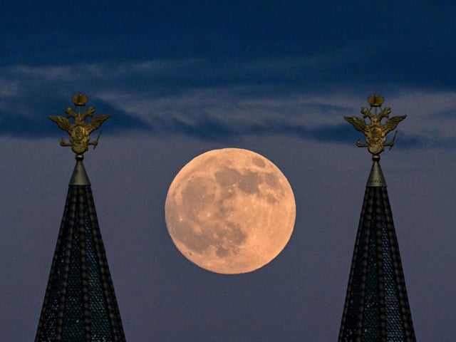 The full moon also known as Flower blood moon is pictured behind the two-headed eagle, the national symbol of Russia atop a building on Red Square in downtown Moscow (Photo by KIRILL KUDRYAVTSEV/AFP via Getty Images)