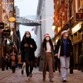 Pedestrians, some wearing face coverings to combat the spread of Covid-19, walk past shops in Covent Garden on the last Saturday for shopping before Christmas, in central London on December 18, 2021. Photo by TOLGA AKMEN/AFP via Getty Images