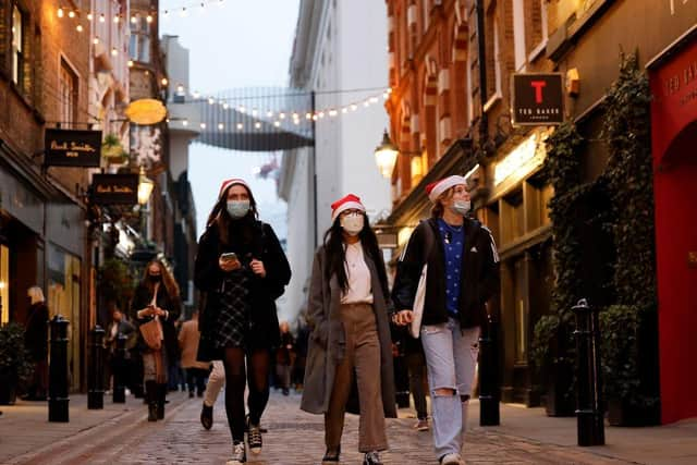 Pedestrians, some wearing face coverings to combat the spread of Covid-19, walk past shops in Covent Garden on the last Saturday for shopping before Christmas, in central London on December 18, 2021. Photo by TOLGA AKMEN/AFP via Getty Images