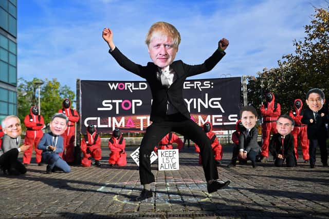 Climate change activists wearing masks depicting images of world leaders, including UK Prime Minister Boris Johnson, take part in a demonstration near the COP26 venue oin Glasgow on Monday