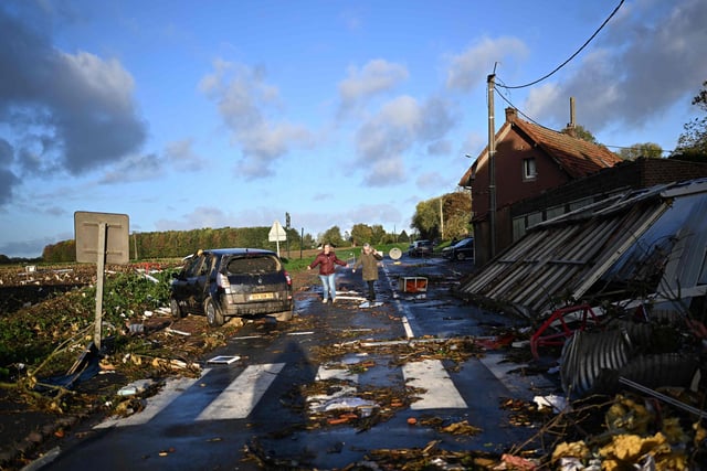 Local residents walk past a damages in Bihucourt, northern France, on October 24, 2022 after a tornado hit the region. (Photo by Sameer Al-Doumy / AFP)