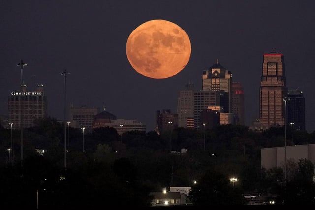 A full Hunter's Moon rises beyond downtown buildings in Kansas City, Missouri.