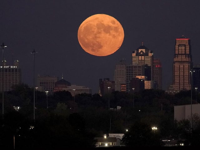 A full Hunter's Moon rises beyond downtown buildings in Kansas City, Missouri.