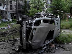 A boy plays on a swing near a destroyed car in a residential area of Mariupol on May 29, 2022, amid the ongoing Russian military action in Ukraine. (Photo by STRINGER / AFP) (Photo by STRINGER/AFP via Getty Images)