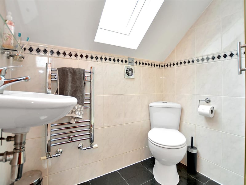 With a modern, three-piece suite with corner tiled shower enclosure. wall hung basin and low flush WC.