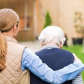 A young carer walking with an elderly woman.