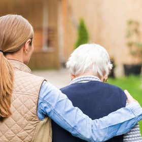 A young carer walking with an elderly woman.