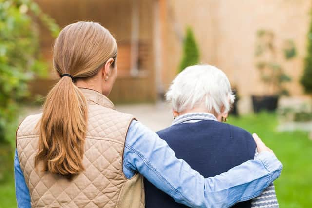 A young carer walking with an elderly woman.