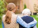 A young carer walking with an elderly woman.