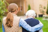 A young carer walking with an elderly woman.