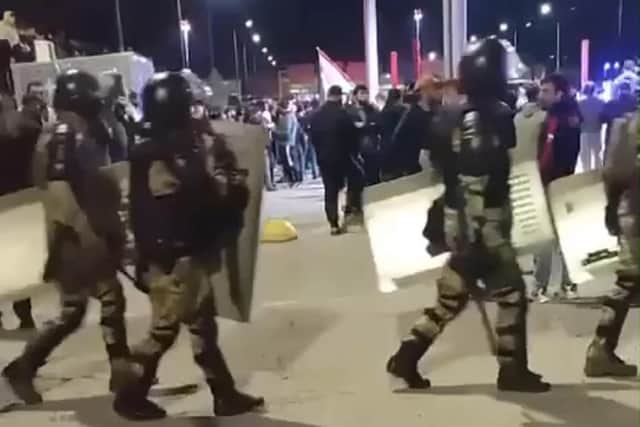 This picture taken from video footage posted on the Telegram channel @askrasul shows law enforcement personnel marching past as protestors gather at an airport in Makhachkala, Russia, where a mob looking for Israelis and Jews gathered after rumours spread that a flight was arriving from Israel.