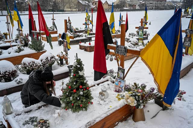 A woman decorates a Christmas tree at the grave of her husband, Oleg Skybyk, a Ukrainian serviceman who was killed resisting the Russian invasion of Ukraine (Picture: Yuriy Dyachyshyn/AFP via Getty Images)
