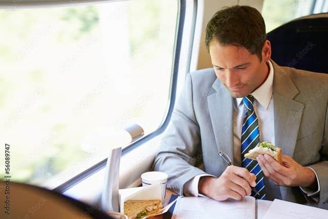 Happy man eating sandwich on train Pic: Adobe