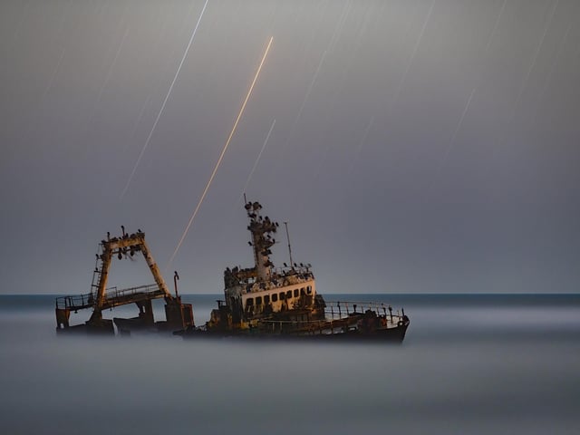 Winner
Zeila © Vikas Chander
The most northerly part of Namibia’s Atlantic facing coast is one of the most treacherous coastlines in the world and has gained the name the Skeleton Coast.
The ship in this photo, Zeila, was stranded on 25 August 2008 and is still in a well-preserved state. The image shows the delicate colours of different star types.
‘I really love how the star trails poking through the grey sky provide a stunning backdrop for this stranded ship. It looks as though it’s floating on a sea of fog. It is a hauntingly beautiful image that would be the perfect setting for a ghost story and is one of my favourites from this year’s competition.’ - Melissa Brobby
Taken with a Nikon D850 camera, 135 mm f/2.8, ISO 200, 30-minute exposure
Location: Heintesbaai (Henties Bay), Erongo Region, Namibia