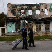 A couple wheel suitcases as they walk in front of a destroyed building in Izyum, Kharkiv Region, eastern Ukraine, amid the Russian invasion of Ukraine.